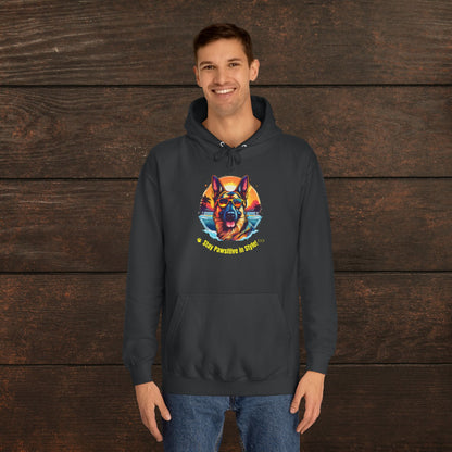 Man wearing a jet black unisex college hoodie featuring a vibrant colorful dog graphic with “Stay Pawsitive in Style” text against a rustic wooden background.