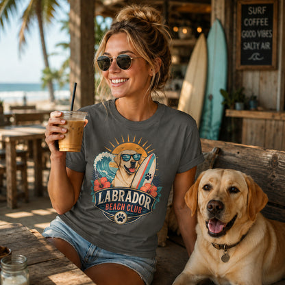 Model wearing a pepper Labrador Beach Club t-shirt with a Labrador in a beach scene