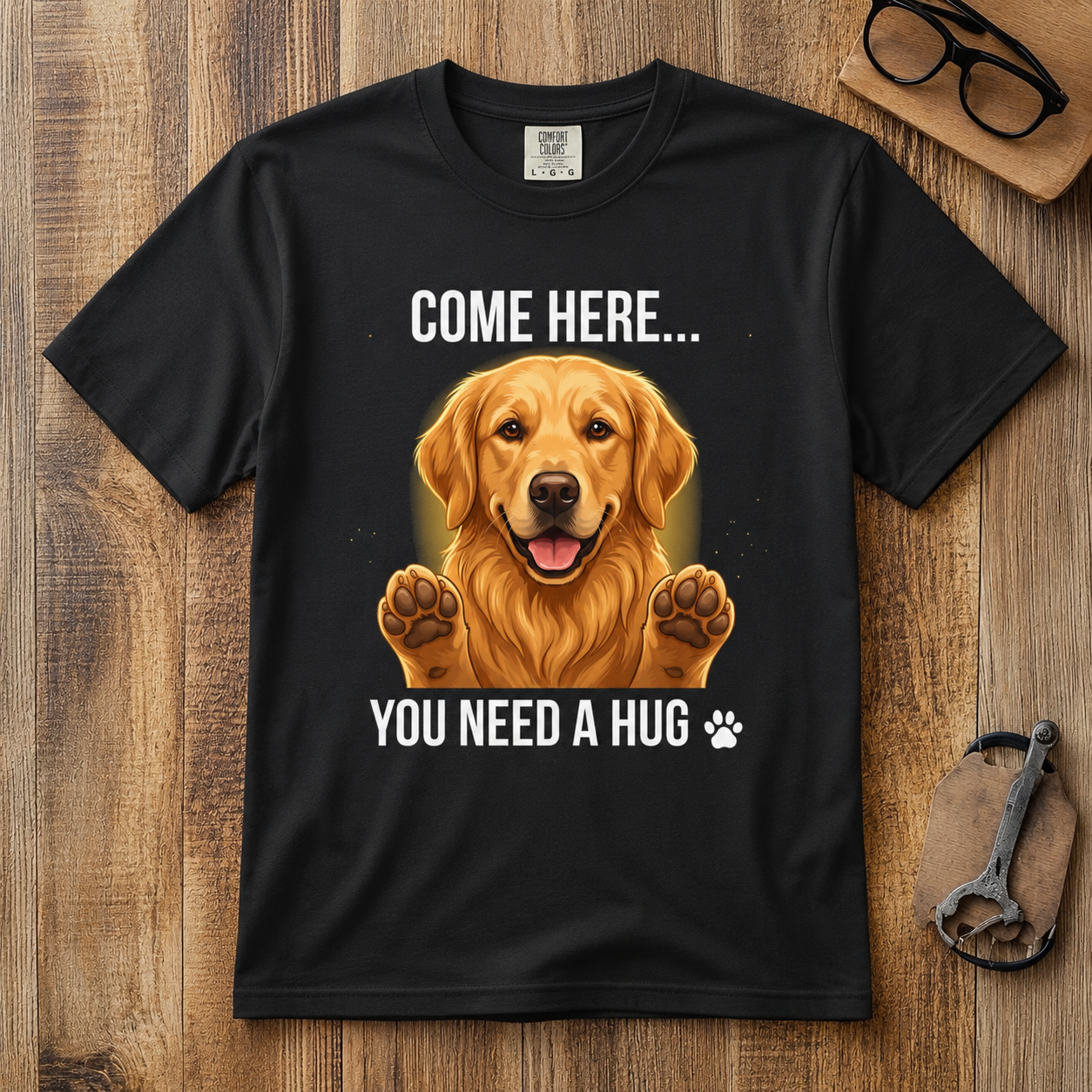 Black Come Here You Need a Hug t-shirt shown flat on a rustic wooden background