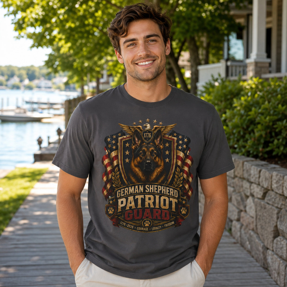 Man wearing a graphite German Shepherd Patriot Guard T-shirt with a German Shepherd patriotic crest design on a lakeside boardwalk.
