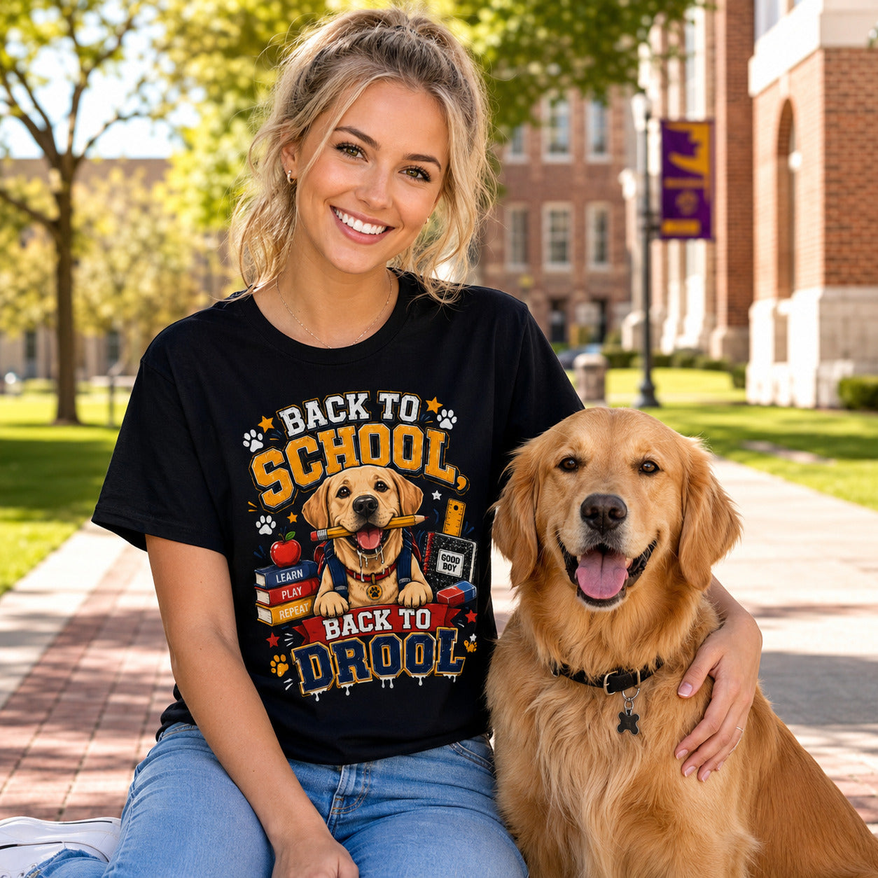 Woman sitting on a campus sidewalk with her golden retriever, wearing black 'Back to School, Back to Drool' dog t-shirt