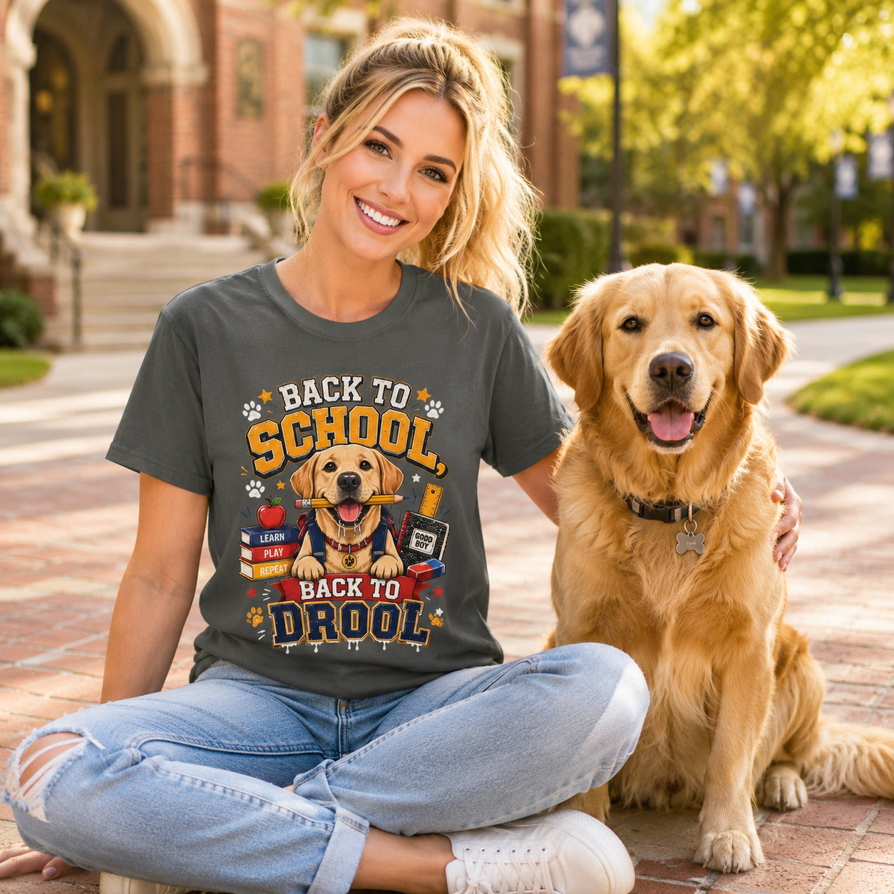 Woman sitting cross-legged on a sidewalk with her golden retriever, wearing pepper 'Back to School, Back to Drool' dog t-shirt