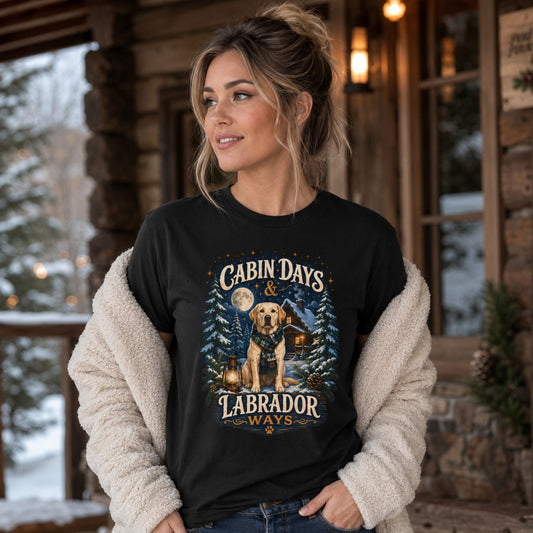 Woman wearing a black Cabin Days & Labrador Ways T-shirt with a Labrador design on a cozy snowy cabin porch.