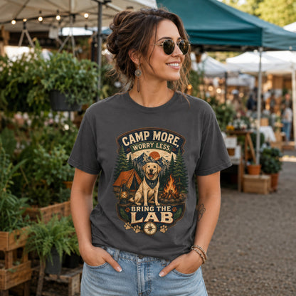 Woman wearing a graphite Camp More Worry Less Bring The Lab T-shirt at an outdoor market with the Labrador camping artwork centered on the chest.