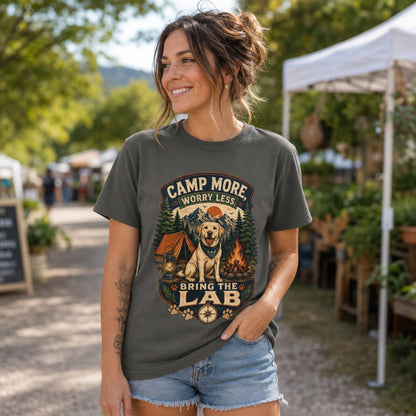 Woman wearing a pepper Camp More Worry Less Bring The Lab T-shirt at an outdoor market with the Labrador camping artwork centered and readable.