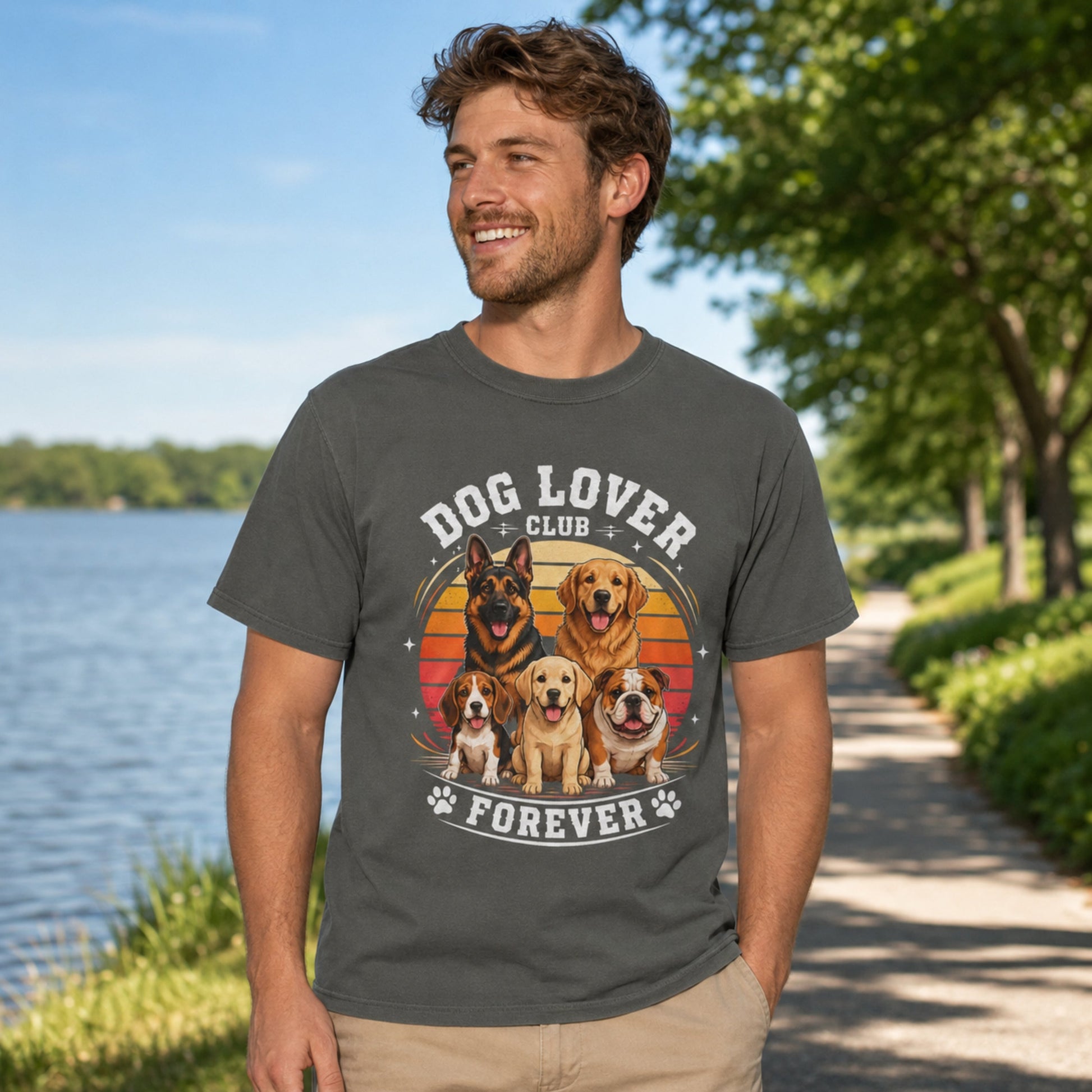 Man wearing a pepper Dog Lover Club Forever T-shirt with multi-breed dog artwork on a lakeside walking path