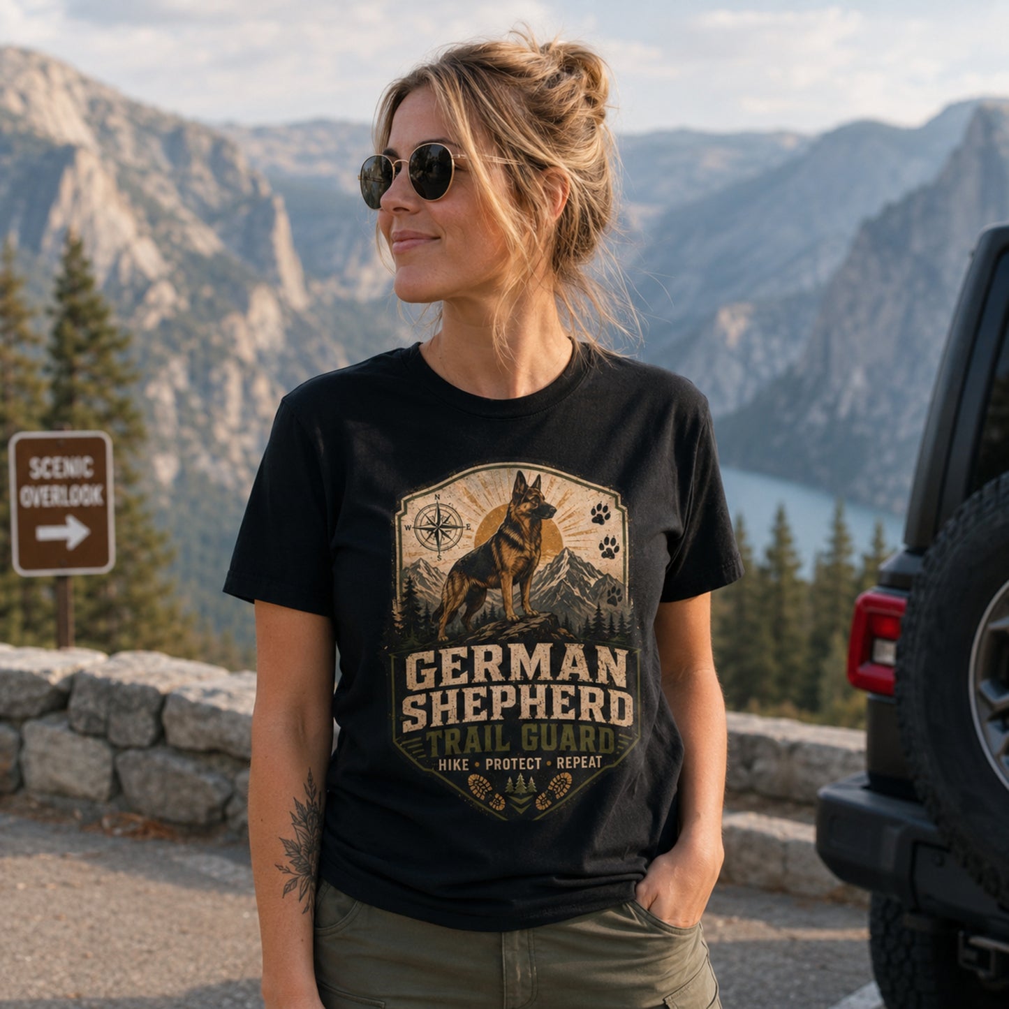 Woman wearing a black German Shepherd Trail Guard T-shirt at a scenic mountain overlook.