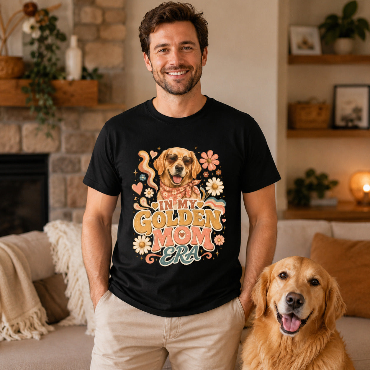 Man sitting by a fireplace with his golden retriever, wearing black 'In My Golden Mom Era' retro floral t-shirt