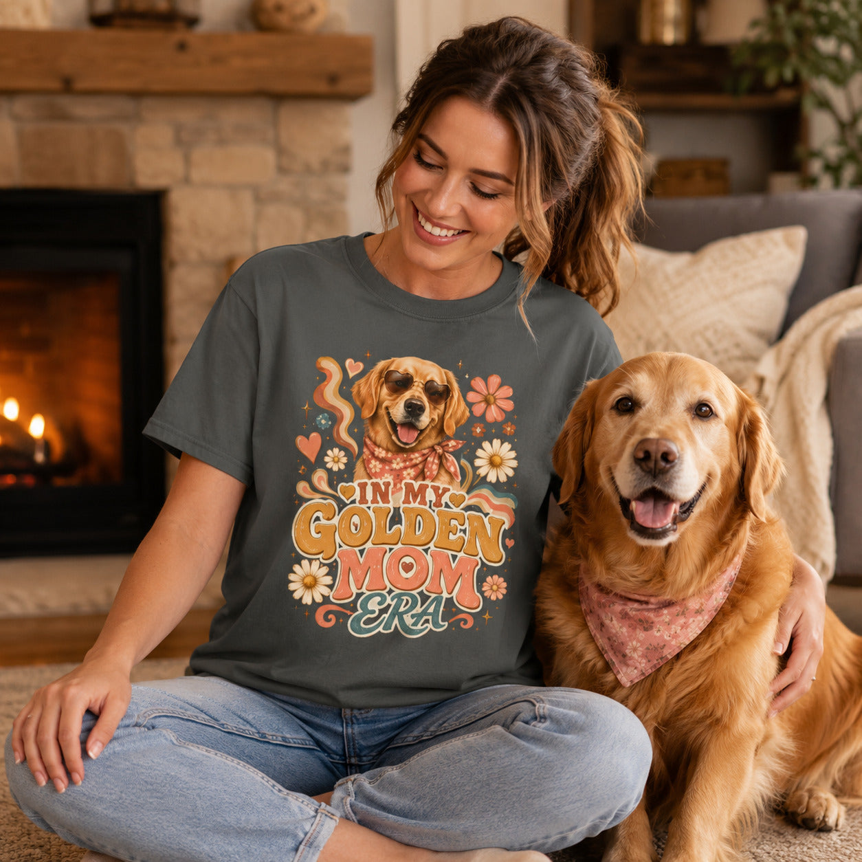 Woman sitting by a fireplace with her golden retriever, wearing pepper 'In My Golden Mom Era' retro floral t-shirt