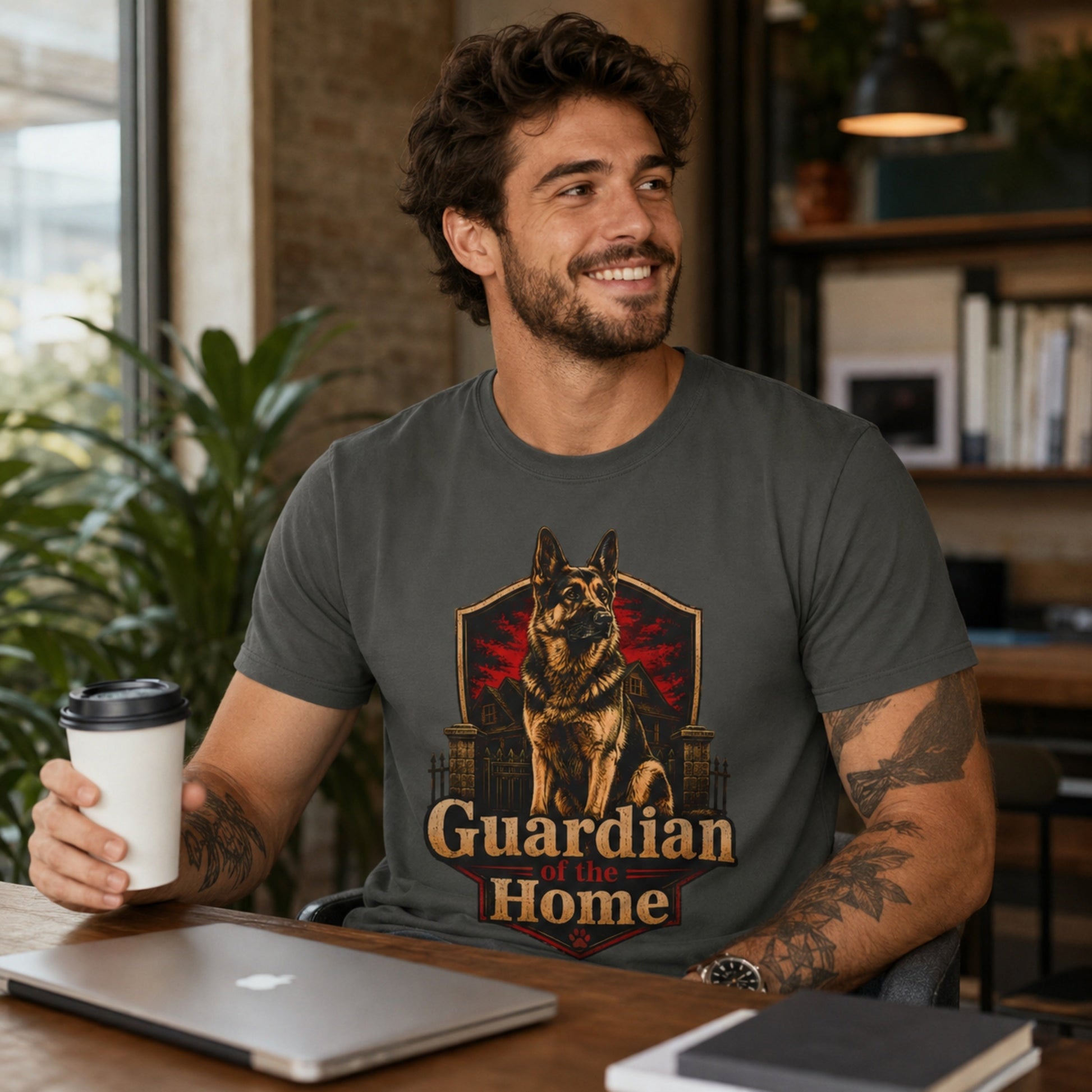Man wearing a pepper Guardian of the Home German Shepherd T-shirt in a home office with coffee and laptop.