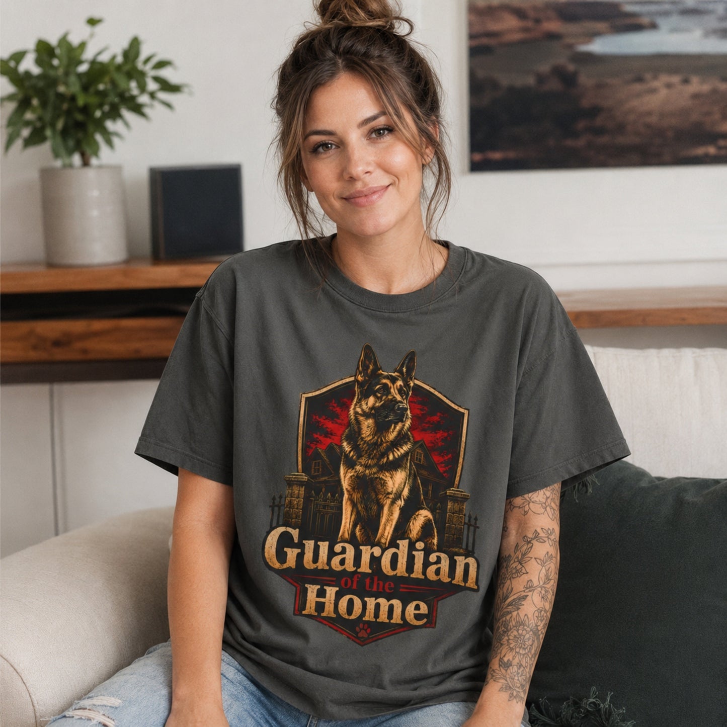 Woman wearing a pepper Guardian of the Home German Shepherd T-shirt while seated on a sofa.
