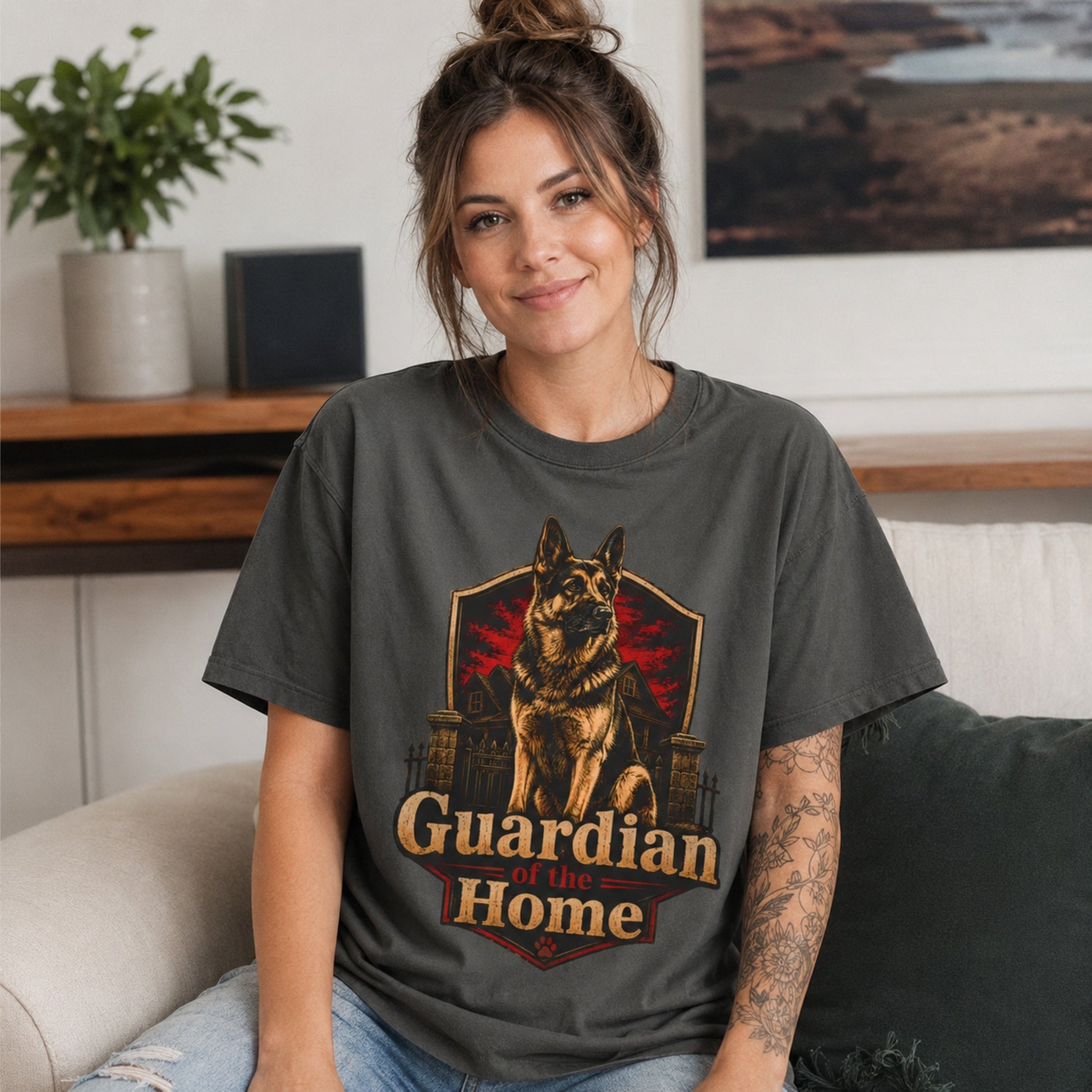 Woman wearing a pepper Guardian of the Home German Shepherd T-shirt while seated on a sofa.