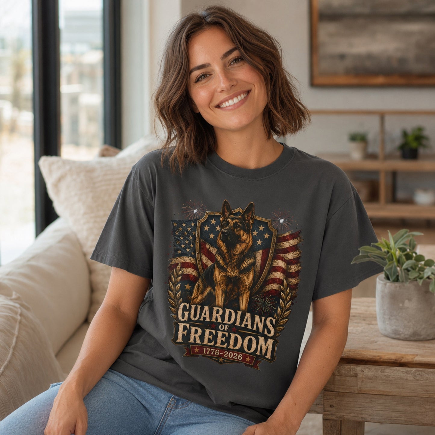 Woman wearing a graphite Guardians of Freedom K-9 T-shirt with a German Shepherd patriotic graphic in a casual living room scene.