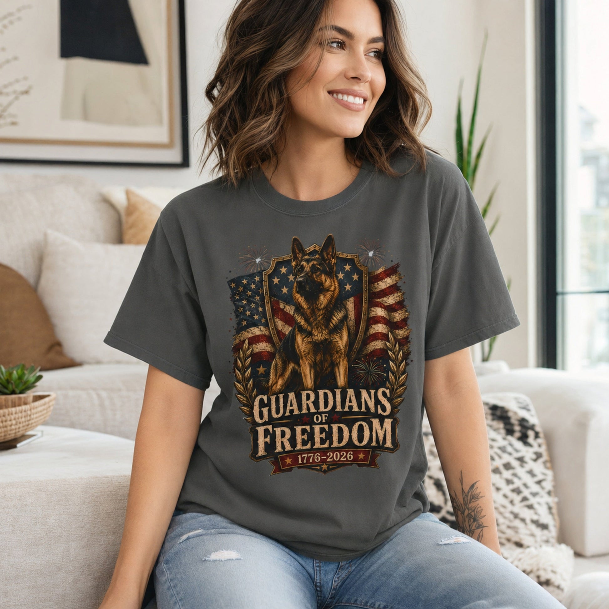 Woman wearing a pepper Guardians of Freedom K-9 T-shirt with a German Shepherd patriotic graphic in a casual living room scene.