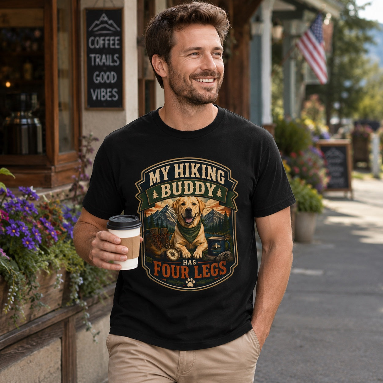 Man in black hiking dog t-shirt holding coffee outside a mountain town coffee shop
