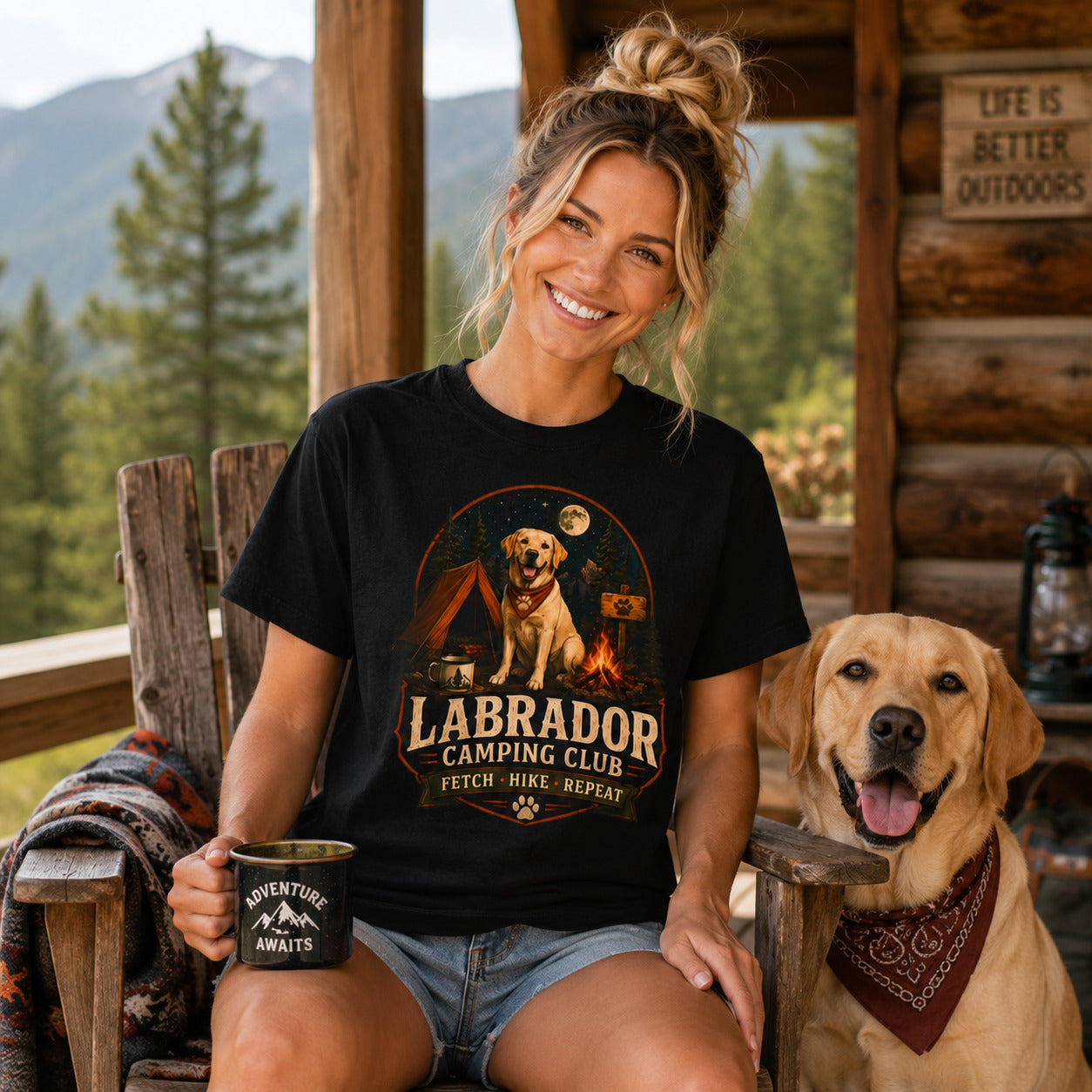 Woman wearing a black Labrador Camping Club Fetch Hike Repeat T-shirt with a Labrador at a mountain lodge.