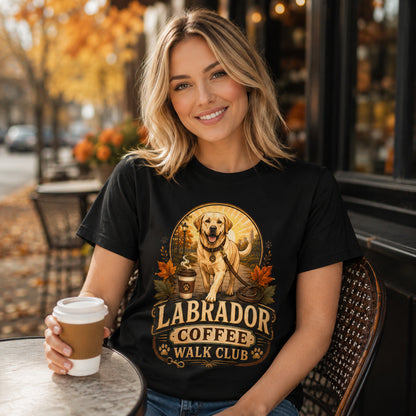 Woman wearing a black Labrador Coffee Walk Club t-shirt holding coffee at an outdoor cafe with a Labrador