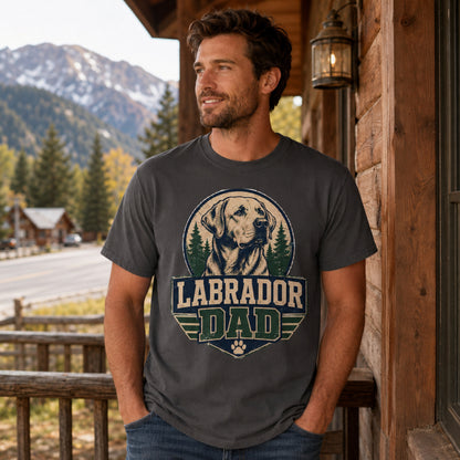 Man wearing a graphite “Labrador Dad” T-shirt on a cabin balcony with a mountain view.