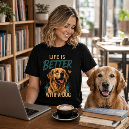 Woman wearing a black Life Is Better With A Dog T-shirt at a table with a laptop, coffee, books, and a golden retriever.