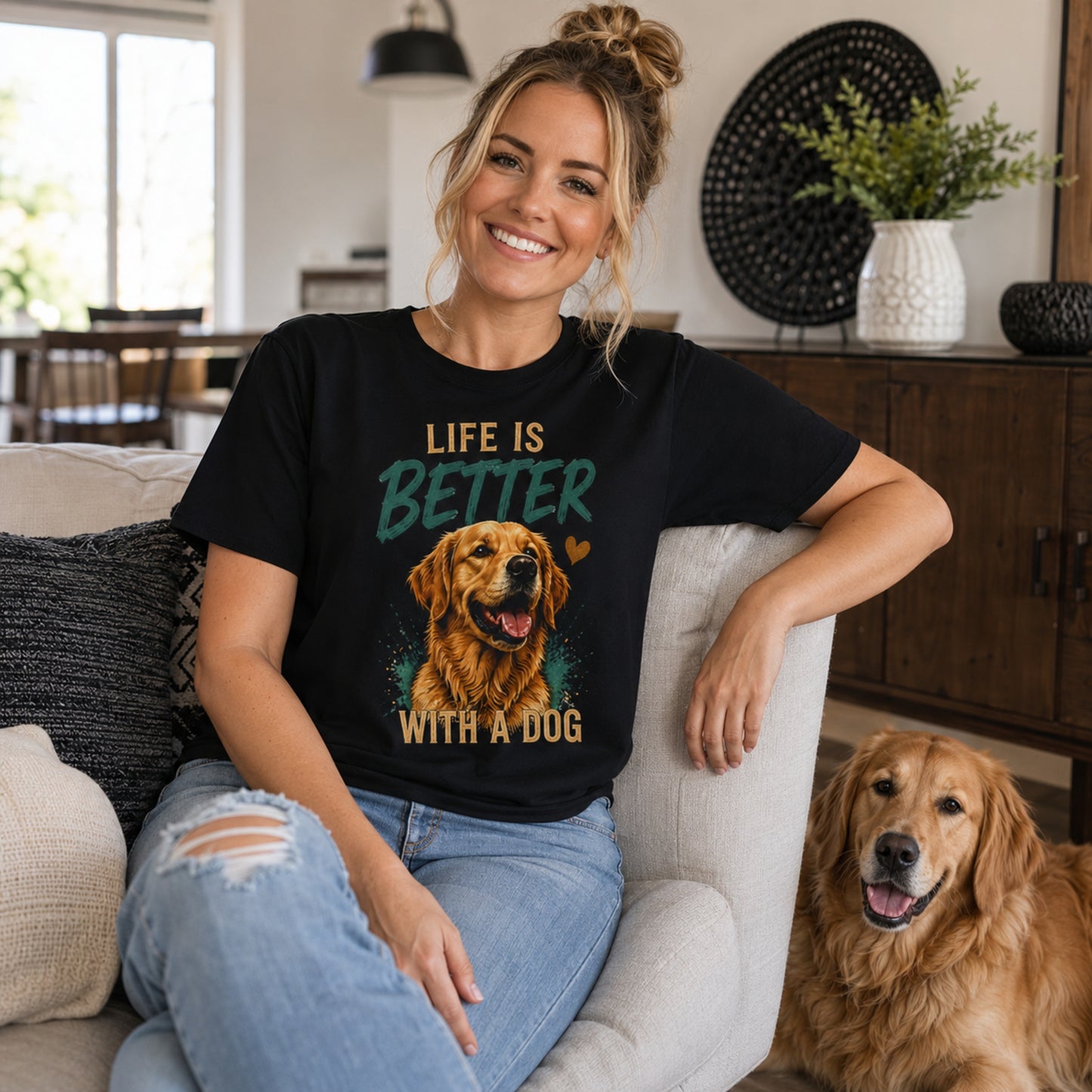 Woman wearing a black Life Is Better With A Dog T-shirt while sitting in a living room with a golden retriever.