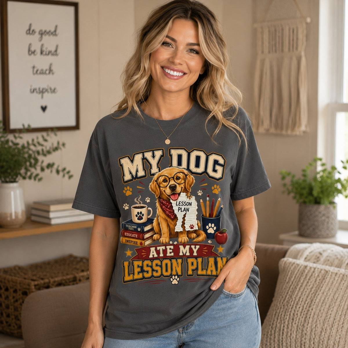 Smiling American woman wearing a Graphite Comfort Colors teacher T-shirt featuring the “My Dog Ate My Lesson Plan” Golden Retriever design in a cozy living room.