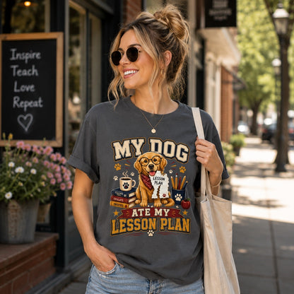 Young American woman wearing a Comfort Colors 1717 Graphite T-shirt featuring the “My Dog Ate My Lesson Plan” Golden Retriever teacher design while walking outdoors with a tote bag.
