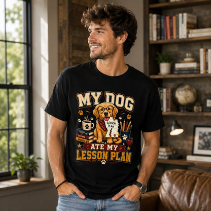 Young man wearing a black “My Dog Ate My Lesson Plan” Golden Retriever teacher T-shirt in a modern home office, featuring a colorful school-themed dog lover graphic with books, coffee mug, pencils, and apple.