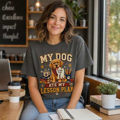 Woman wearing a Pepper “My Dog Ate My Lesson Plan” T-shirt in a coffee shop with laptop, coffee, books, and golden retriever teacher artwork.