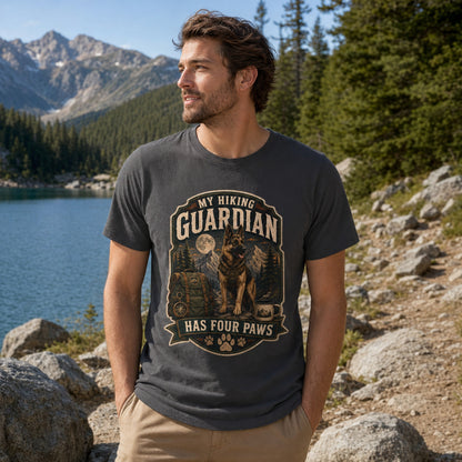 Man wearing a graphite “My Hiking Guardian Has Four Paws” T-shirt with a German Shepherd design near a lakeside hiking trail.