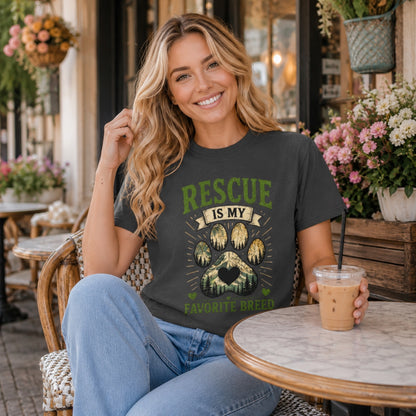 Woman wearing a graphite Rescue Is My Favorite Breed T-shirt at an outdoor cafe with iced coffee.