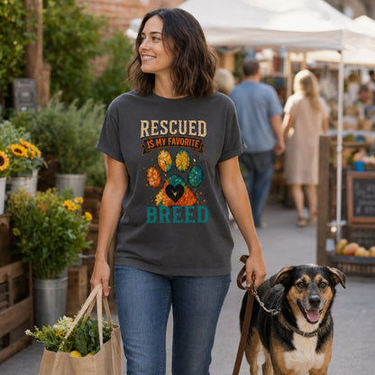 Woman wearing a graphite Rescued Is My Favorite Breed T-shirt at a farmers market with a shopping bag and rescue dog.