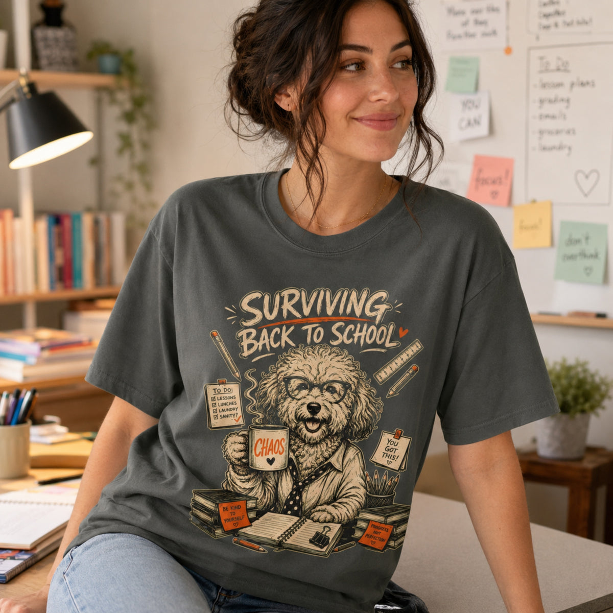 Woman wearing a pepper Surviving Back to School dog teacher T-shirt in a home office.