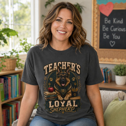 Woman wearing a graphite Teacher’s Loyal Shepherd T-shirt with a German Shepherd graphic in an indoor teacher workspace scene.