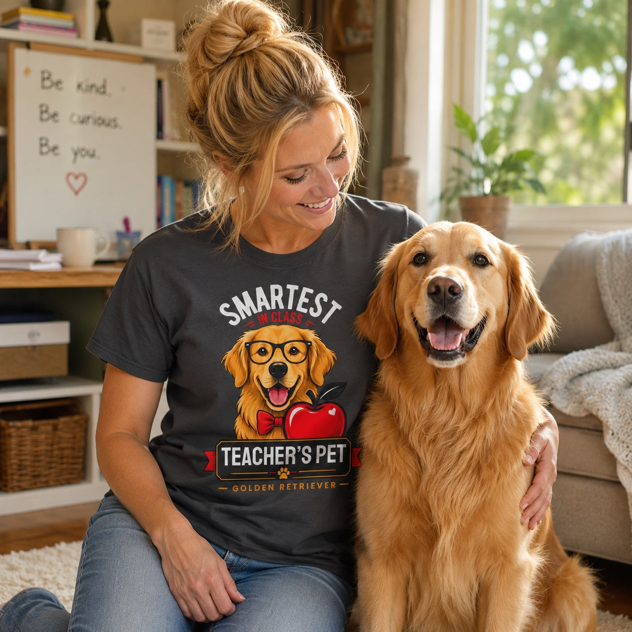Woman sitting on a couch with her golden retriever, wearing graphite 'Teacher's Pet Golden Retriever' t-shirt