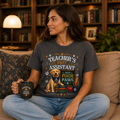 Woman wearing a graphite Teacher's Best Assistant Has Four Paws T-shirt with a Labrador classroom helper design in a home library while holding a mug.